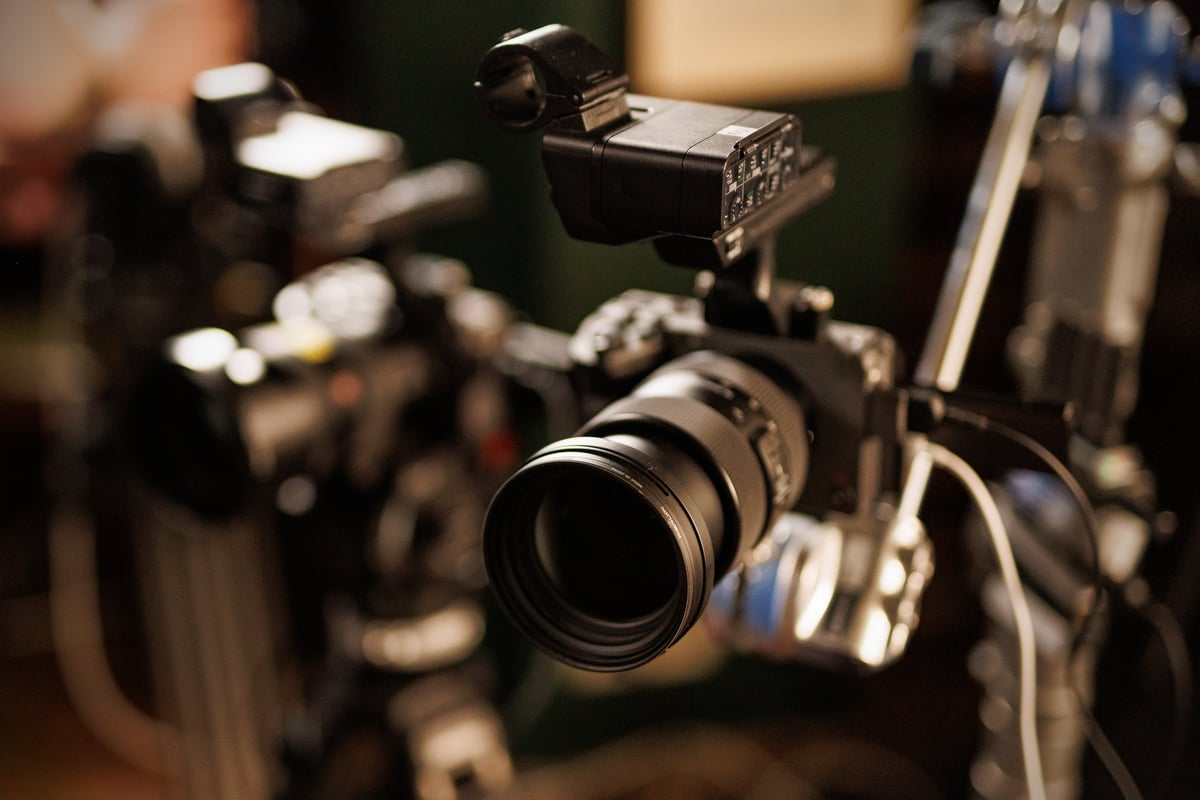 Close-up of a high-end digital movie camera with a large lens and production accessories in a filming environment