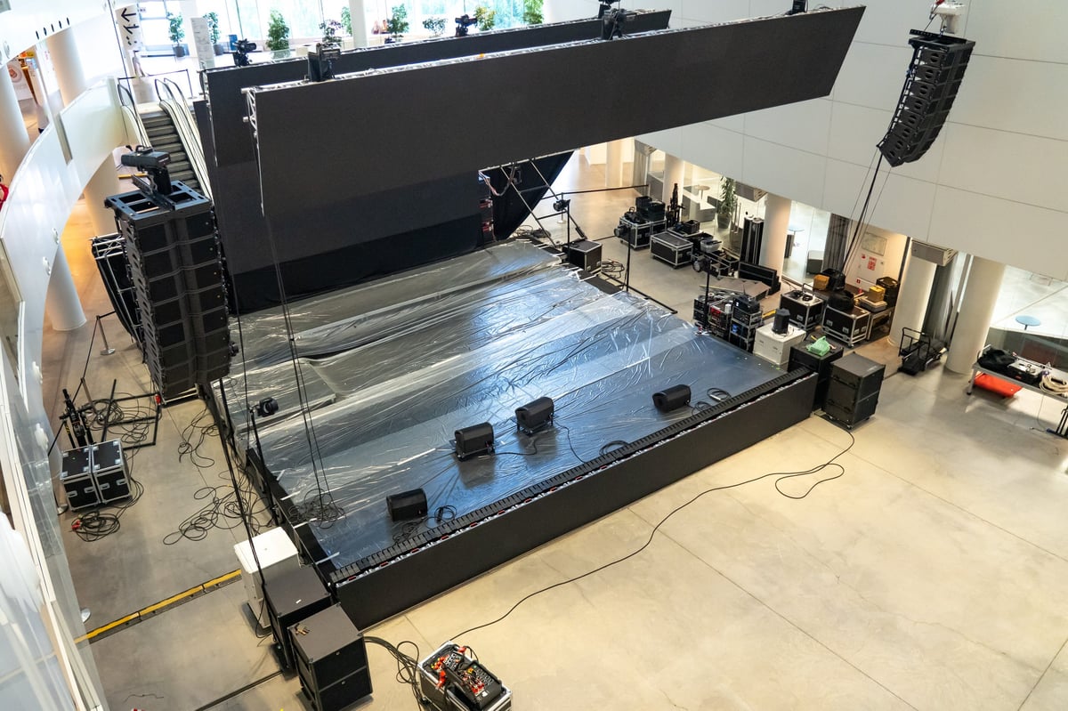 Comprehensive concert stage setup in a modern indoor venue highlighting sound equipment, lighting rig and the performance area