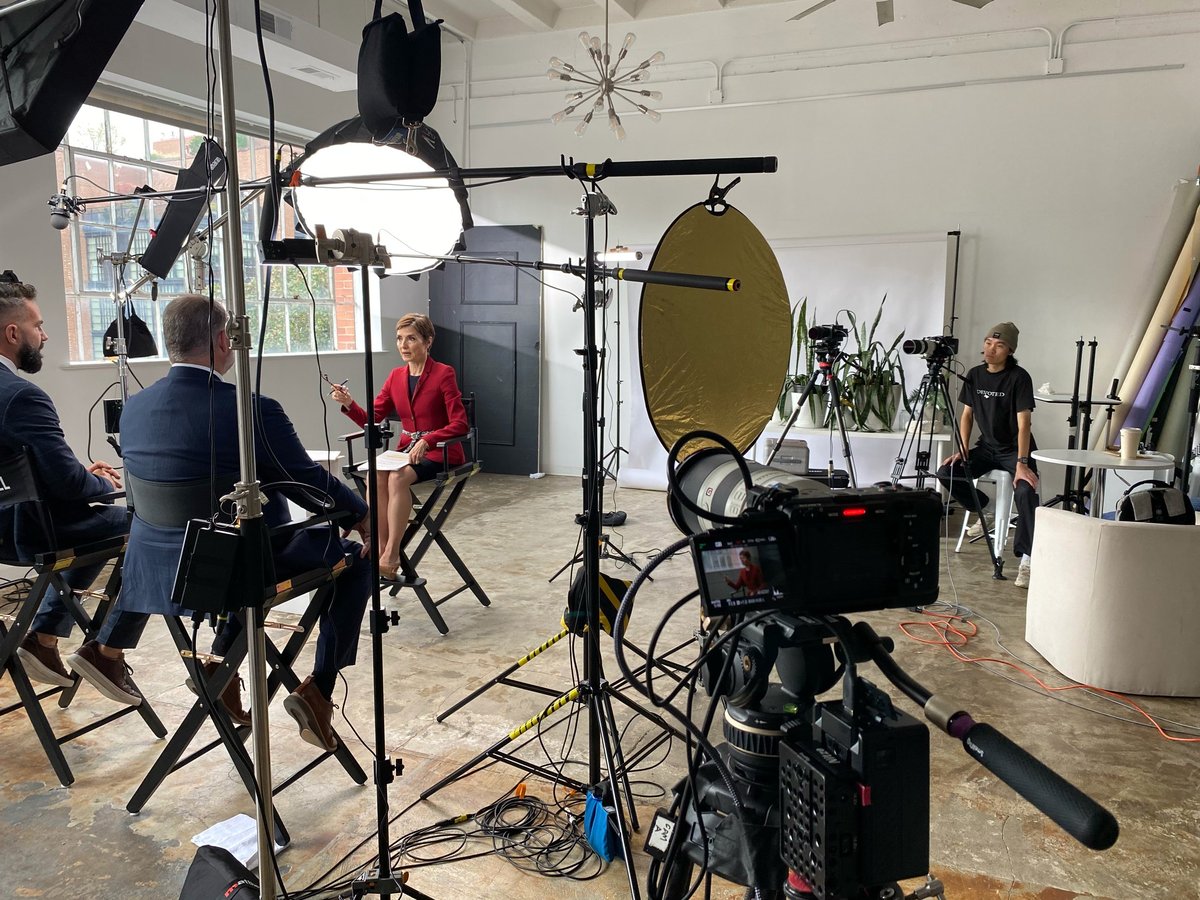 Professional film set with camera equipment, lighting rigs, reflectors, and crew members in a studio space