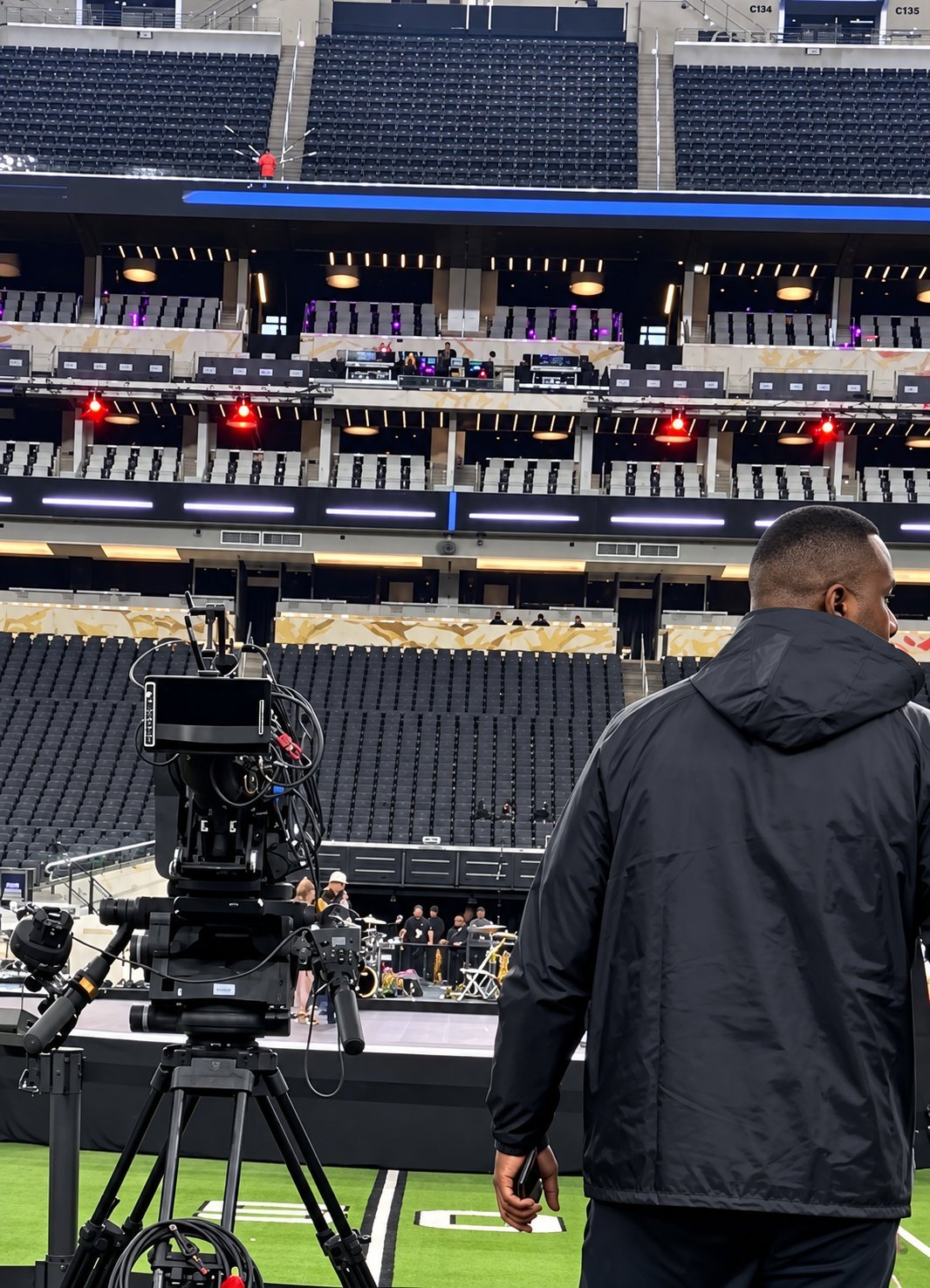 Cameraman operating a broadcast camera on a stadium field with empty seating