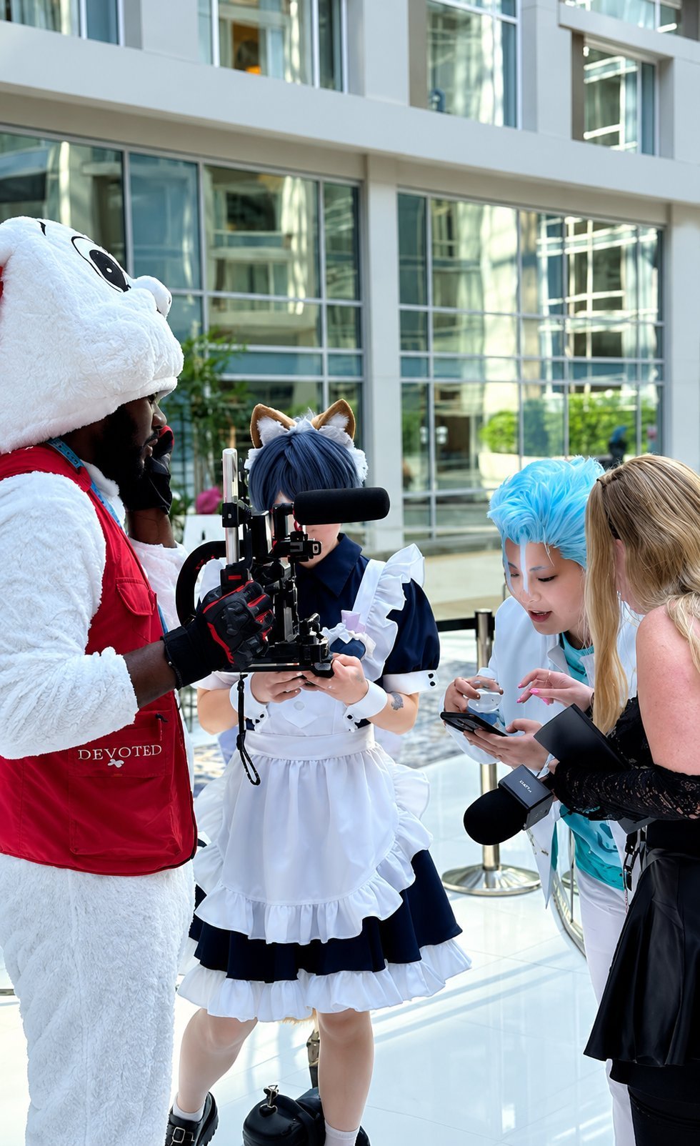 Costumed characters and children performing on a street with modern glass building in the background