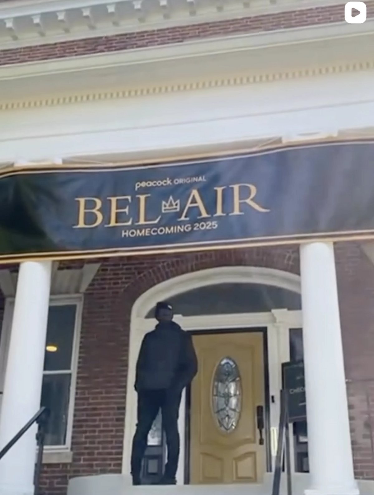 Blue banner for Peacock Original Bel-Air Homecoming 2025 displayed above entrance with white columns and brick exterior