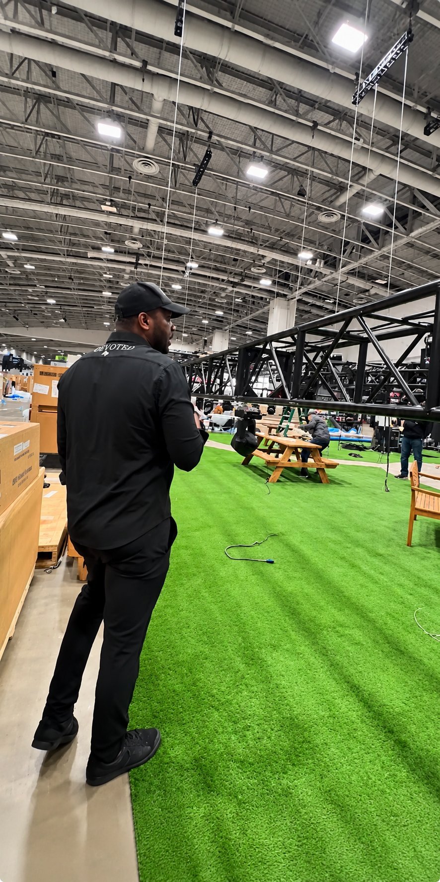 Crew member in DEVOTED gear walking through an indoor sports facility during setup