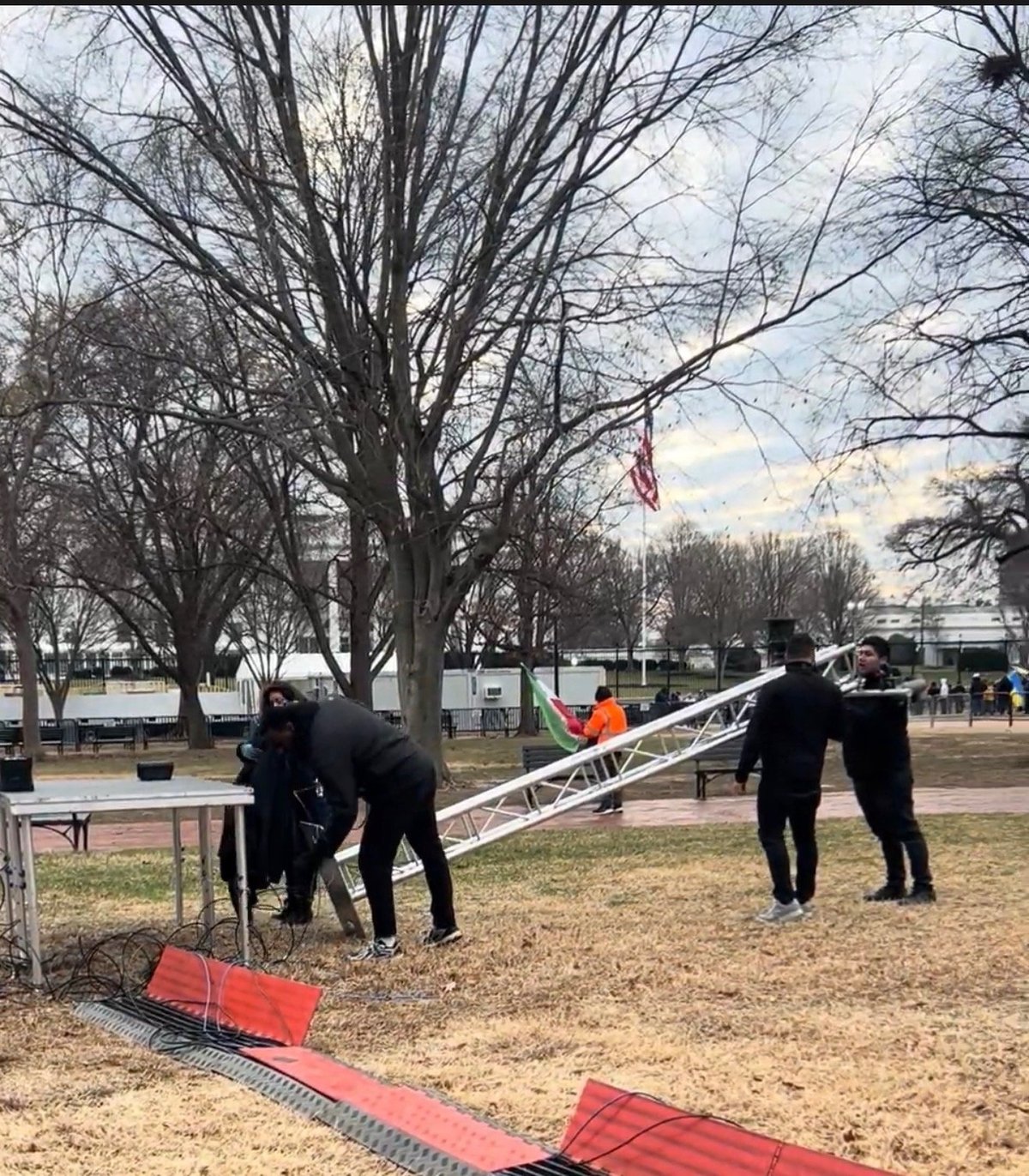Crew members assembling a frame structure outdoors at an event staging area