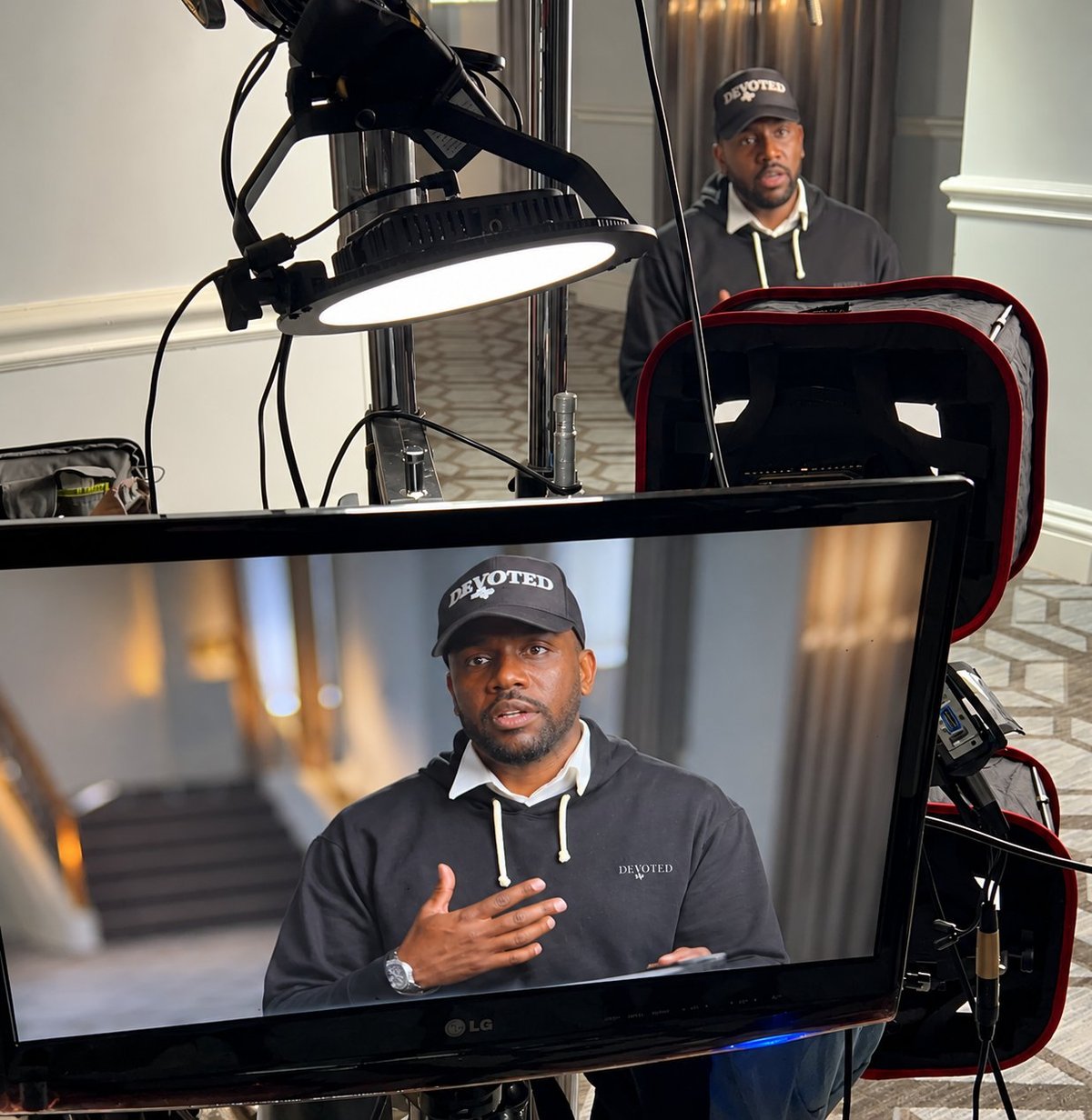 Video interview setup showing a man on a monitor with a ring light and professional recording equipment in a studio setting