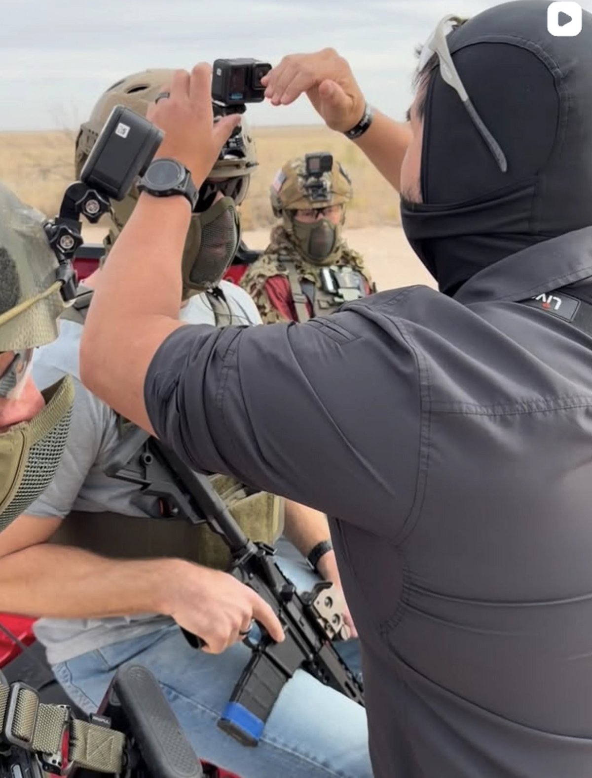 Person in tactical gear filming with action camera mounted on arm rig during outdoor training exercise
