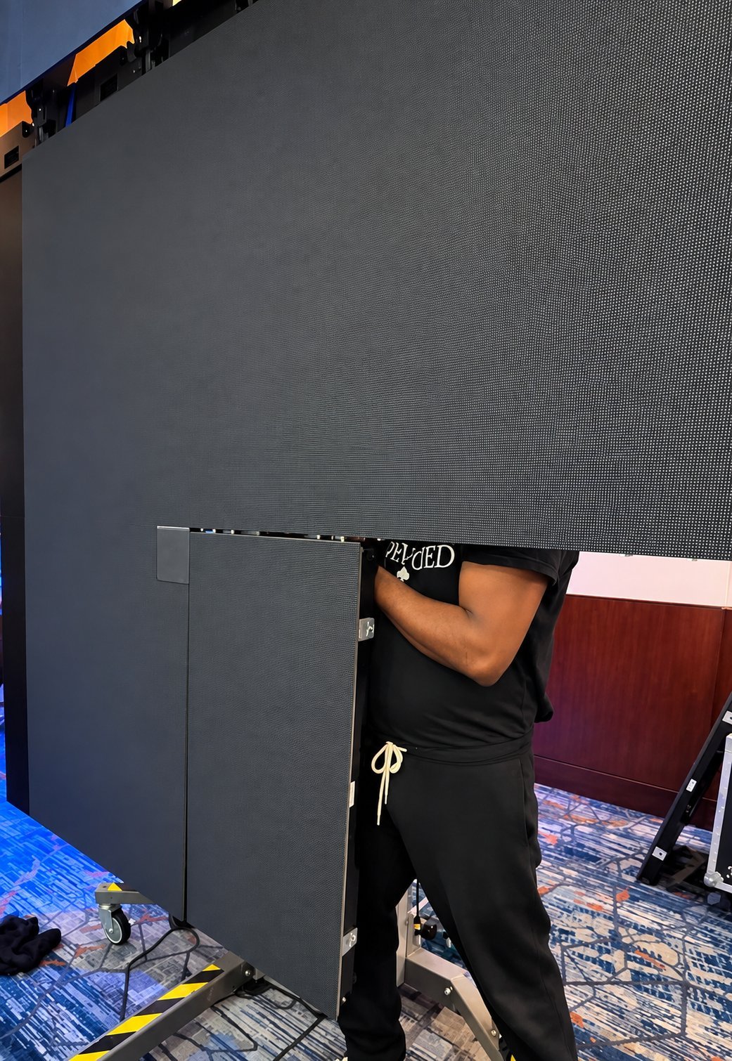 Crew member adjusting a large LED display panel at an indoor event venue